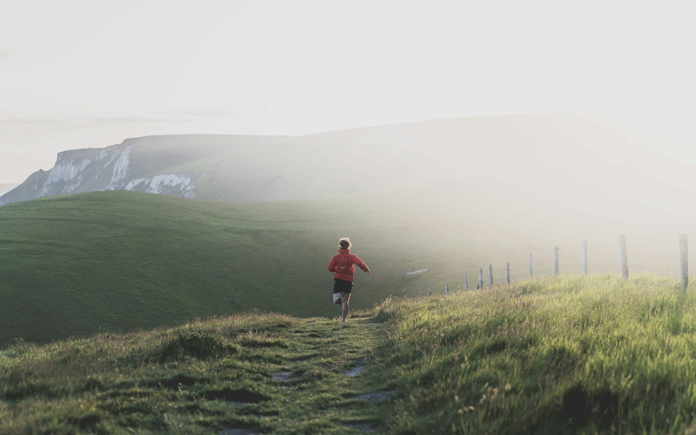 A man running along a misty mountain trail
