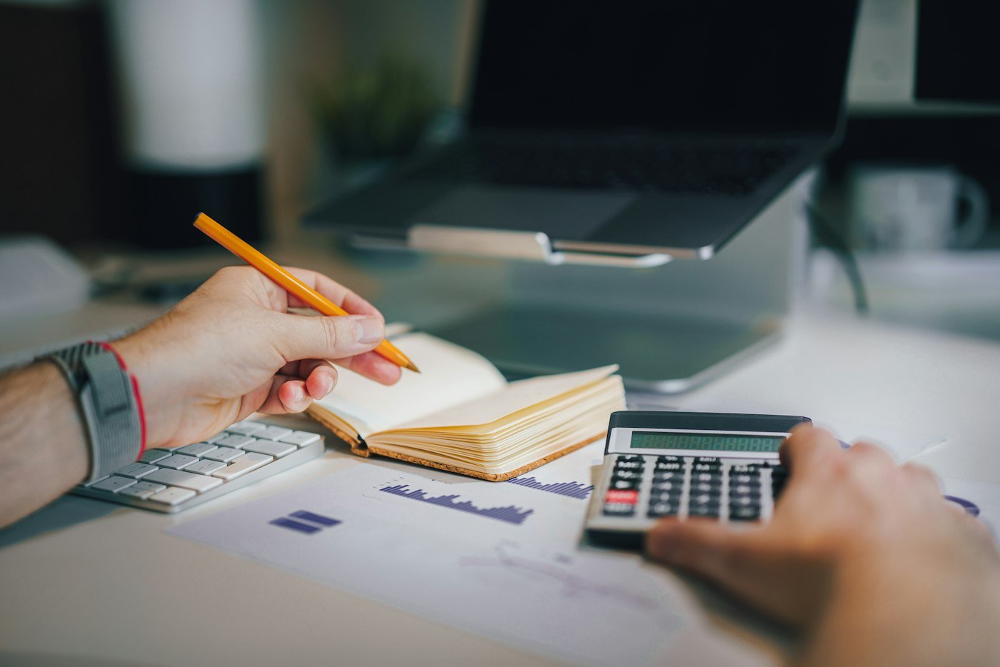 A notebook, pencil, calculator and printed charts on a desk