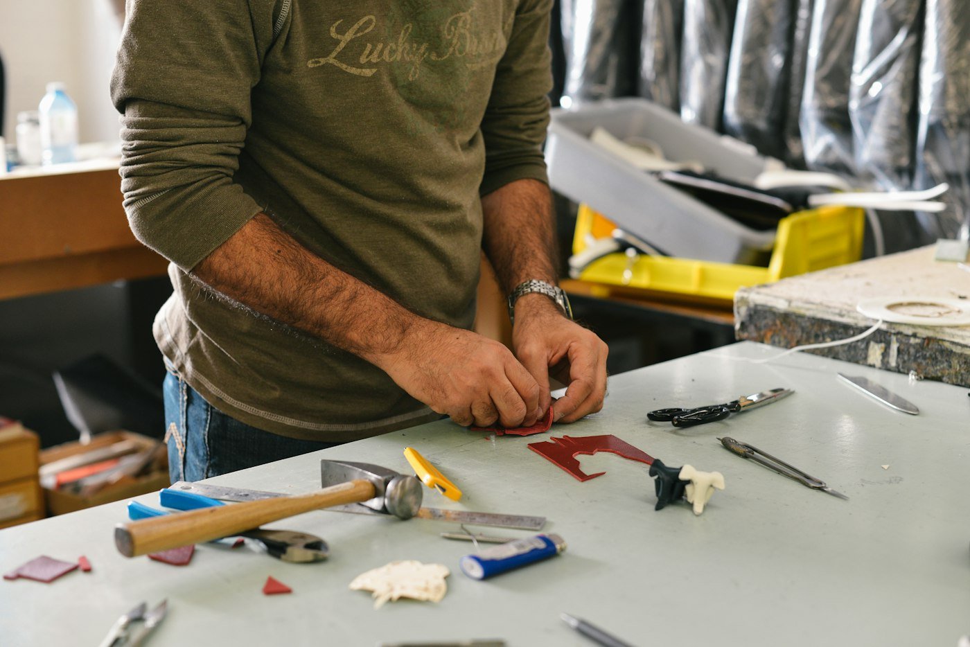 A man's hands working with a hammer and tools at a workbench