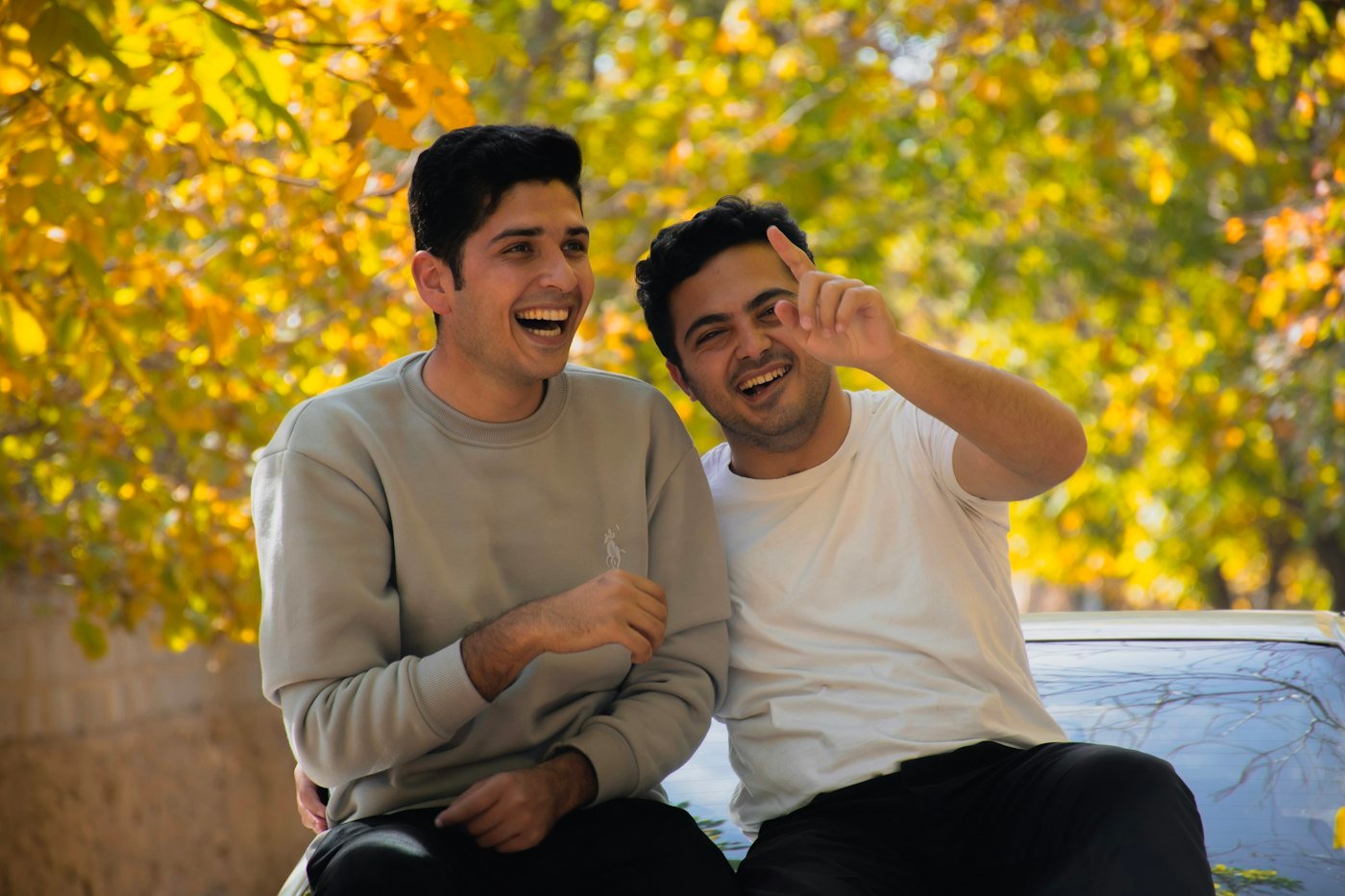 Two men laughing together as they sit side by side