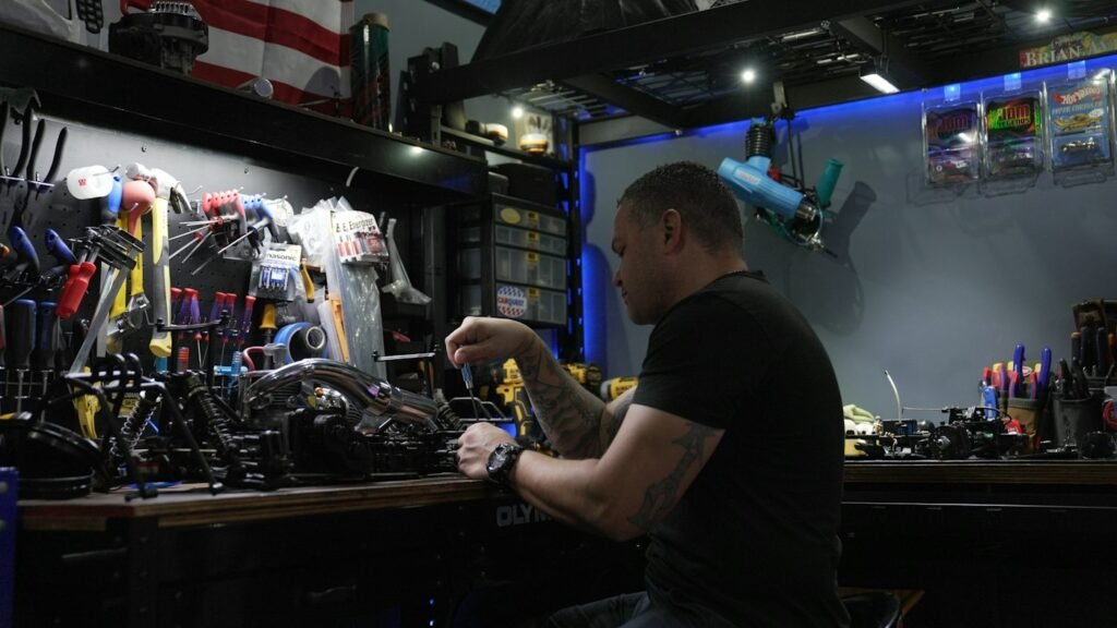 A man working with his hands on a machine at a workshop bench
