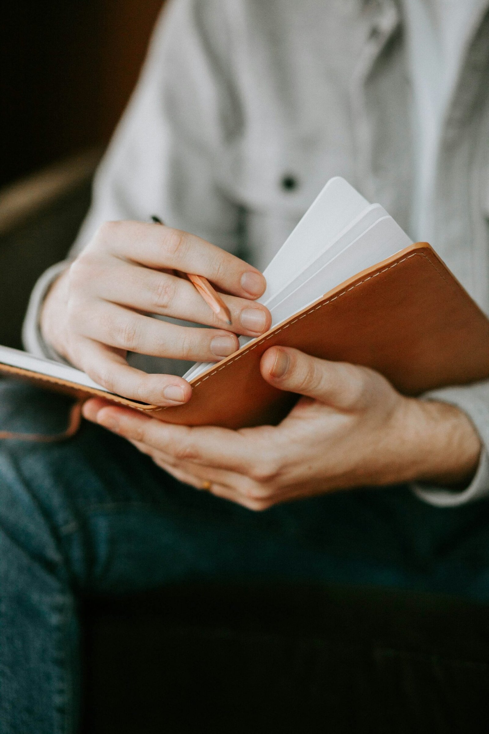 Hands holding an open notebook and pencil