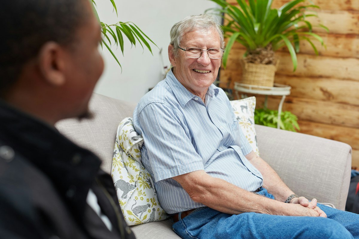 A smiling older man relaxing on a sofa in conversation