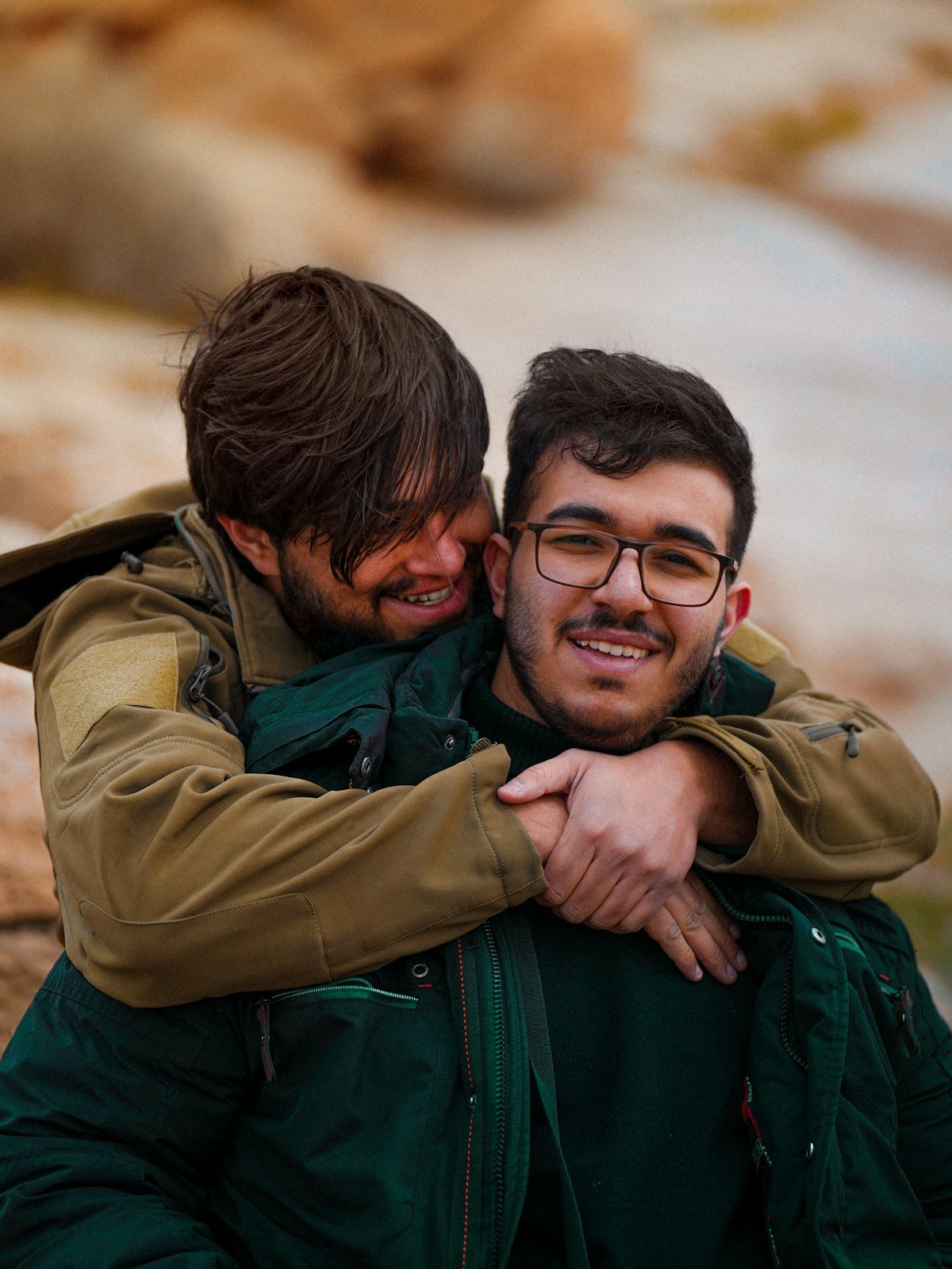 Two young men smiling and embracing outdoors